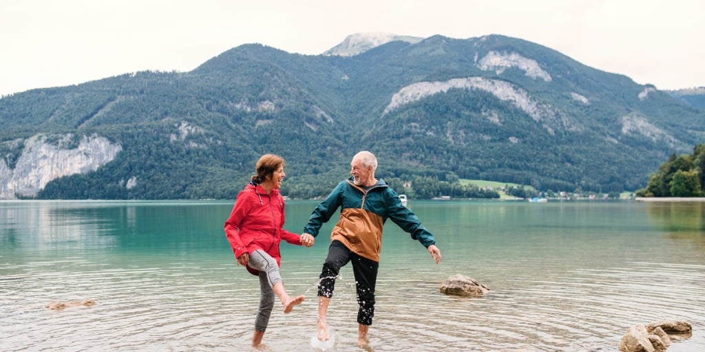 senior pensioner couple hikers standing barefoot in lake in nature picture id1191391272