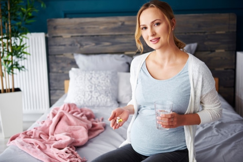 pregnant woman taking medicine and drinking water