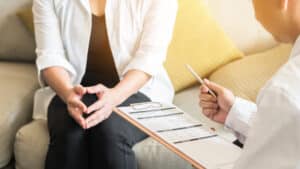 Woman speaking with OBGYN who takes notes during a well-woman visit for cervical cancer prevention