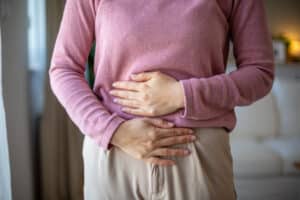 Close up of a woman clutching her lower abdomen, in pain from endometriosis and in need of treatment.
